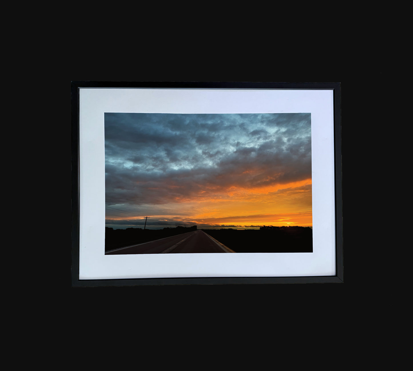 Fine art print of large clouds and sunset over road. Framed view