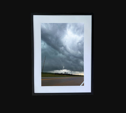 Fine art print of large storm clouds  building over a train and factory.  Framed view