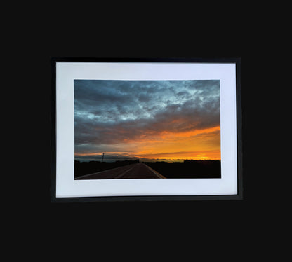 Fine art print of large clouds and sunset over road.  Framed view