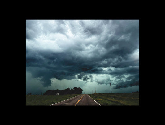 Fine art print of large storm clouds  building over a rural road.  Print view