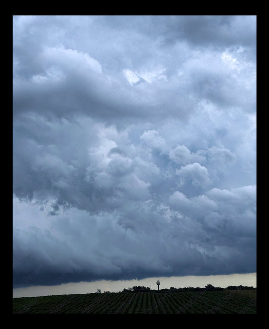 Fine art print of large storm clouds  building over a rural town and corn field.  Print view